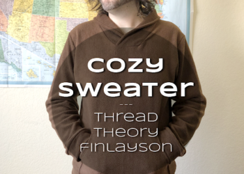 Ryan in a brown sweater, hands in the kangaroo pocket, standing in front of a map of the USA. Text overlay reads Cozy Sweater: Thread Theory Finlayson