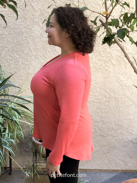 Side view of woman wearing a coral orange Laela Jeyne Samantha sweater