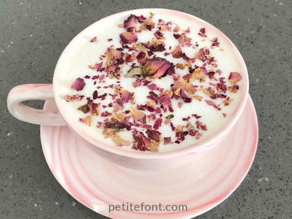 Rose latte in pink cup and saucer topped with rose petals served at Meant to Be Café in Alamitos Beach, Long Beach
