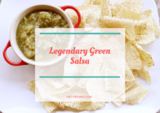 White platter with tortilla chips around a red bowl filled with green salsa with white box overlay and red text that reads Legendary Green Salsa petite font dot com