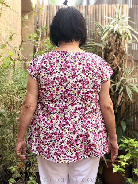 Back view of a woman with short black hair modeling New Look 6414 sewing pattern in floral quilting cotton.