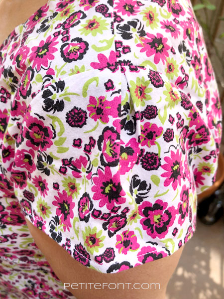 Close up view of pleated sleeve head detail on a floral cotton blouse