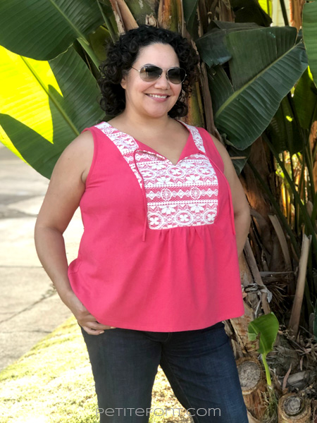 Front view of a smiling curly haired Latina woman wearing a sleeveless pink silk and lace handmade Phoenix blouse