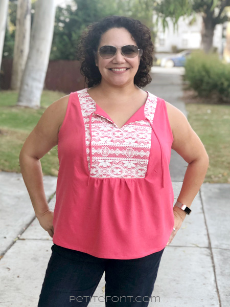 Front view of a smiling curly haired Latina woman wearing a sleeveless pink silk and lace handmade Phoenix blouse