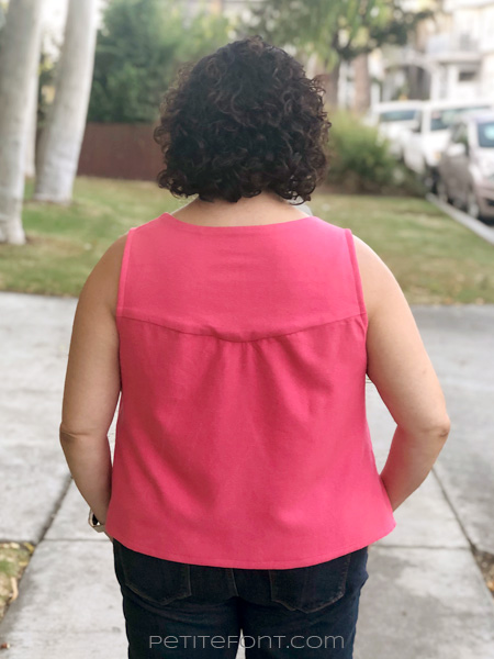 Back view of curly haired Latina woman wearing a sleevelss pink silk handmade Phoenix blouse