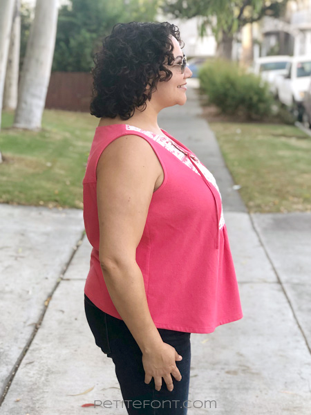 Side view of a smiling curly haired Latina woman wearing a sleeveless pink silk and lace handmade Phoenix blouse