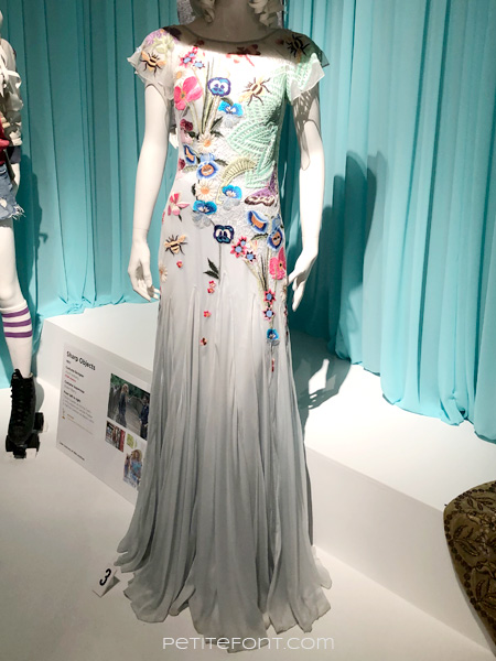 Image of a mannequin wearing a very delicate grey blue mesh dress with ornate bird and flower embroider all around, from FIDM's 13th Art of Television Costume Design exhibit