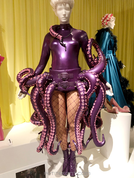 Image of a mannequin wearing the Esme Squalor costume: a purple latex leotard with purple octopus-like tentacles around the waist, fishnet stockings, and purple patent leather ankle boots, from FIDM's 13th Art of Television Costume Design exhibit