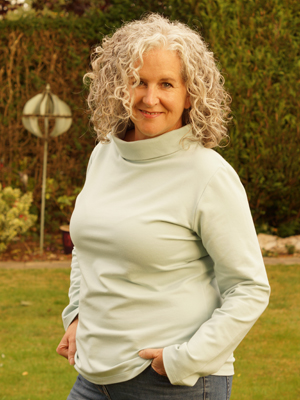 Blogger Carol in a white turtleneck with hands in her pockets
