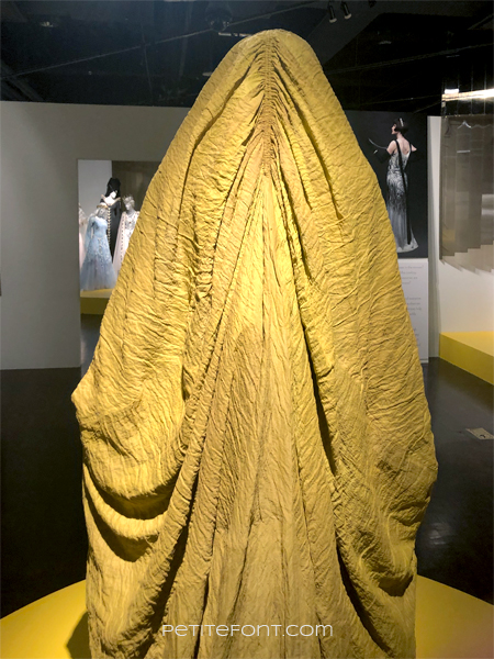 Closer view of the back of costume showing ruching around the head of the yellow Aki-Aki character from Star Wars as seen at the 2020 movie costumes exhibit at FIDM