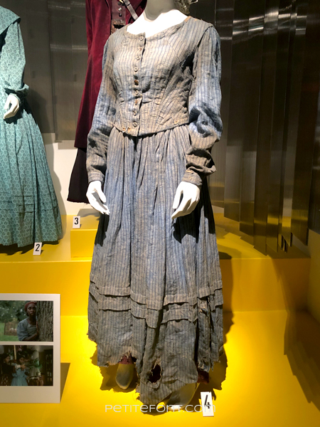 Torn and dirty pinstriped blue dress from Harriett, at the 2020 movie costumes exhibit at FIDM