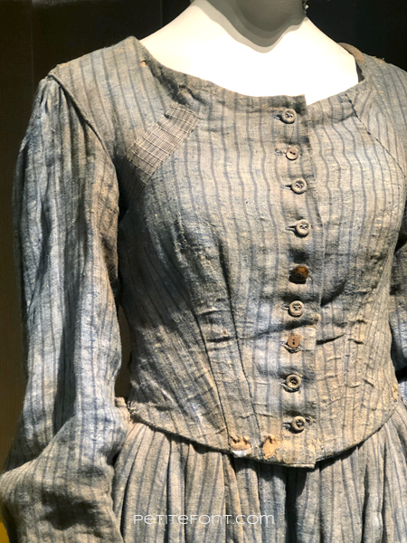 Close up of the torn and dirty pinstriped blue dress from Harriett, at the 2020 movie costumes exhibit at FIDM
