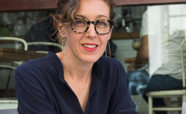 Headshot of Liesl Gibson wearing glasses, dangly earrings and a dark blue shirt