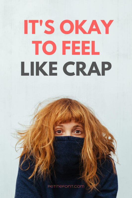 Top of a redheaded woman's face hiding in a black sweater with text above that reads It's Okay to Feel Like Crap PetiteFont.com
