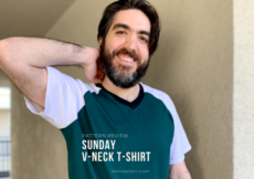 Dark haired man with a beard in a color blocked green and white t-shirt and light brown cargo shorts. He has a hand behind his neck and is smiling at the camera. White text overlay reads Pattern Review: Sunday V-neck T-shirt.