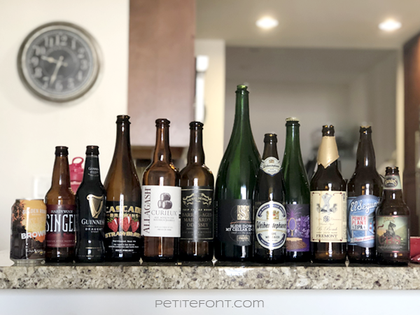 A collection of 12 different beer cans and bottles on a granite countertop