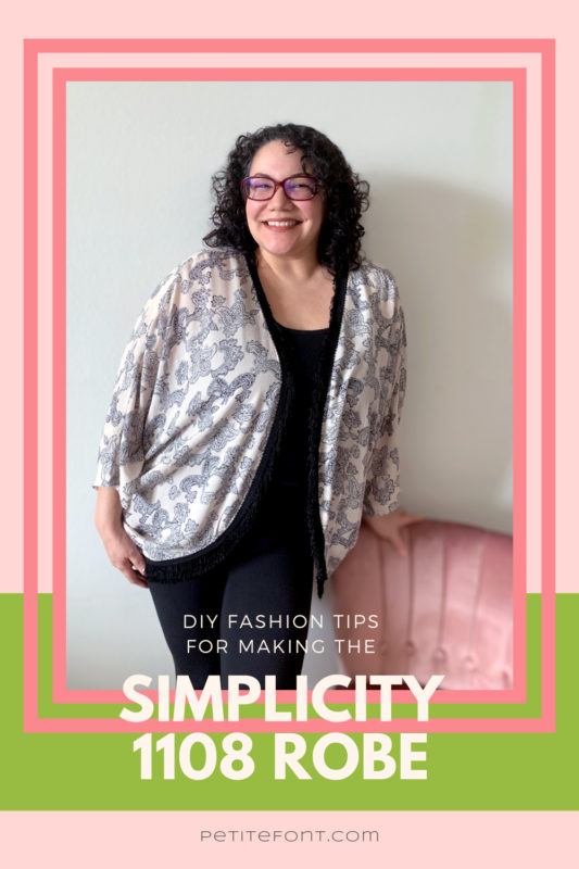Curly hair bespectabled woman in all black except a peach and black open robe, leaning against a pink chair. The picture is in a double pink frame on top of a pink and green background. Text overlay reads "DIY fashion tips for making the Simplicity 1108 robe"