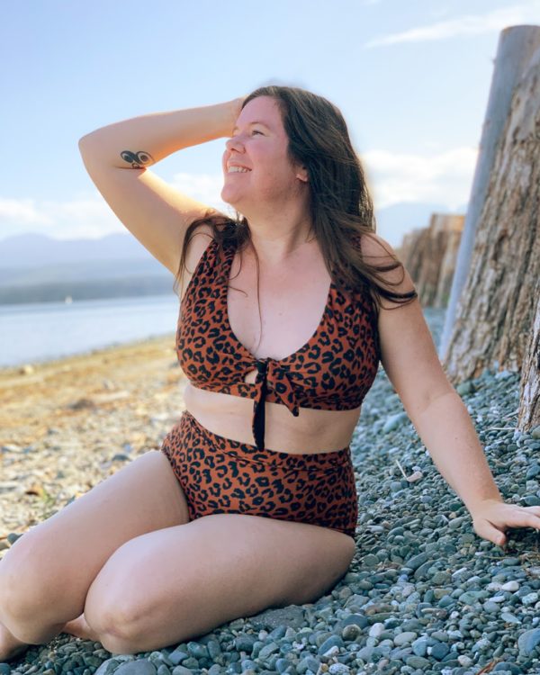 Helen sitting in a shaded spot on the beach in a leopard print bikini