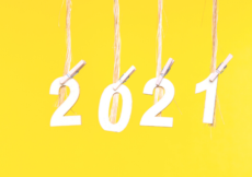 Yellow background with the numbers 2021 hanging from individual pieces of twine