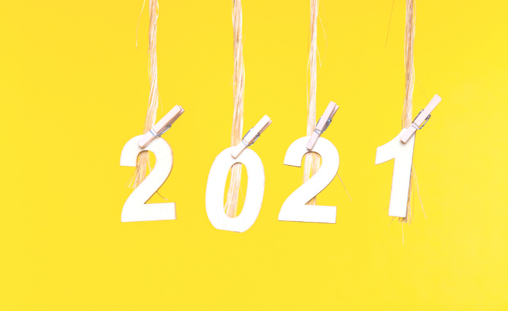 Yellow background with the numbers 2021 hanging from individual pieces of twine