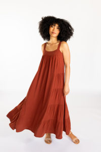 Woman with a beautiful large mane of curls against a white background in a deep amber Marcel tank dress