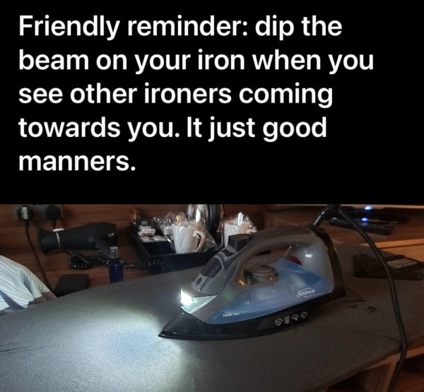 Image of an iron with a headlight sitting on an ironing board in a dark room. Text reads "friendly reminder: dip the beam on your iron when you see other ironers coming towards you. It's just good manners."