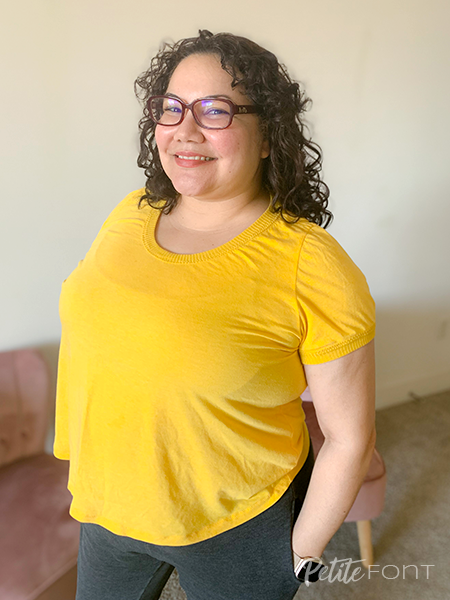 Paulette smiles at the camera while wearing a bright yellow t-shirt